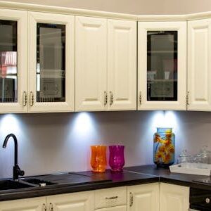 A stylish modern kitchen with white cabinets and colorful decor pieces.